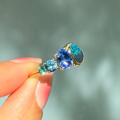 An Australian Opal Ring by NIXIN Jewelry. The ring is held at an angle that catches the light, showing the exceptional color and brilliance of the lightning ridge opal ring. This is a truly unique jewelry creation.