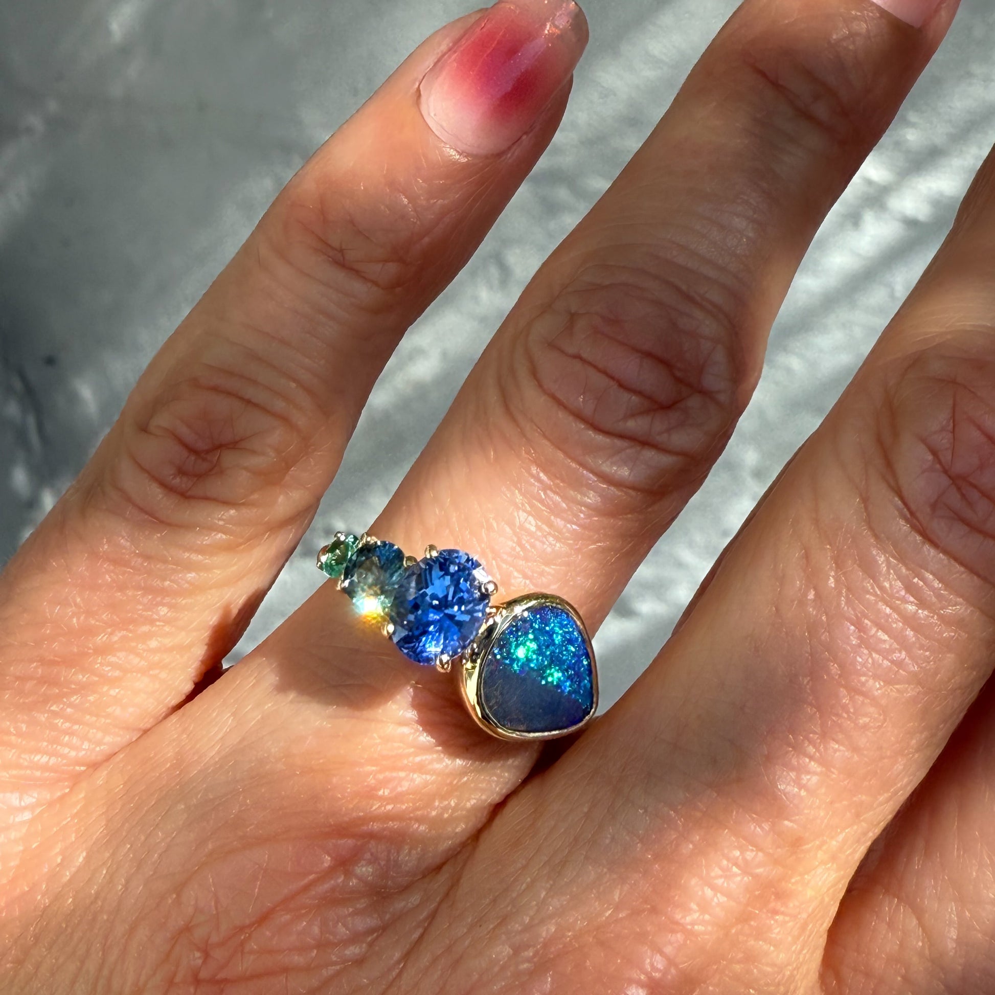 An Australian Opal Ring by NIXIN Jewelry. The luxury ring is worn on a hand, highlighting its elegant fit and the captivating blue opal colors that make this a unique piece of luxury jewelry.