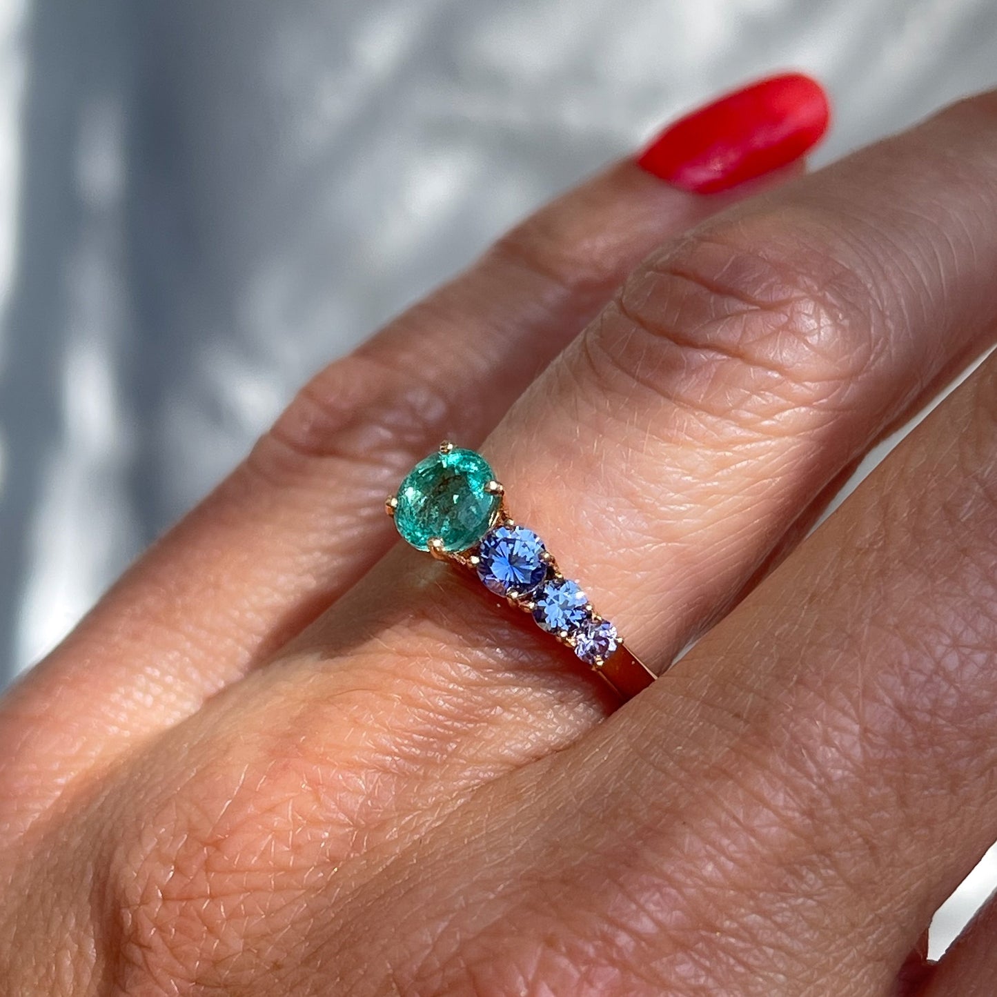 A Colombian Emerald Ring by NIXIN Jewelry modeled on the hand. The sapphire and emerald ring is 14k rose gold and makes a beautiful emerald engagement ring.