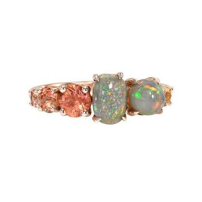 An Australian Opal Ring by NIXIN Jewelry. A stunning black opal ring with grey base tone and vivid pinfire. This women's luxury ring is prong set with natural, rich peach ombre sapphires, classifying it as rare opal jewelry. This luxury jewelry piece is designed as unique jewelry art.