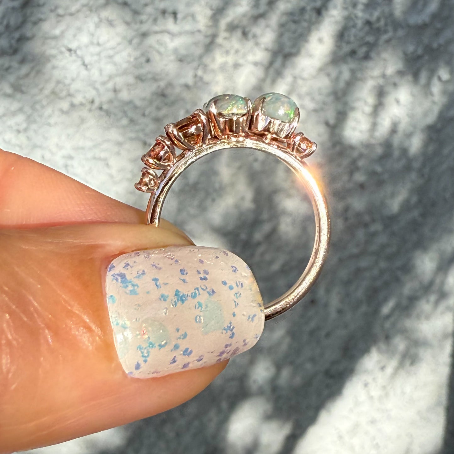 An Australian Opal Ring by NIXIN Jewelry detailing the prong setting that maximizes light interaction with the semi black opal.s This side profile shot highlights the smooth rose gold opal ring band and its suitability as a unique fine jewelry statement piece. This luxury ring is an investment in jewelry art.