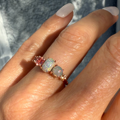 An Australian Opal Ring by NIXIN Jewelry worn on a hand in natural sunlight, highlighting the shimmering sapphire opal ring cascade. This modern opal ring features two lightning ridge opal gems, making it a true cocktail ring for the discerning client. Search for this unique opal ring for sale.