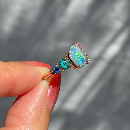 Side view of an Australian Opal Ring by NIXIN Jewelry made with a blue opal and a zambian emerald.