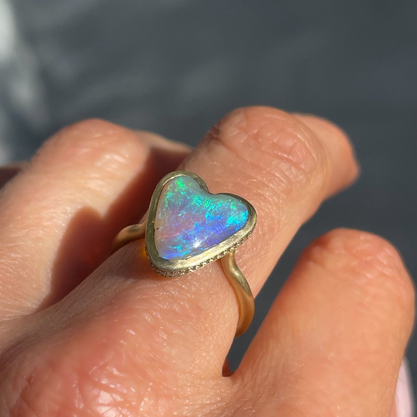 Angled view of an Australian Opal Ring by NIXIN Jewelry showing pave diamonds in the side of the heart ring.