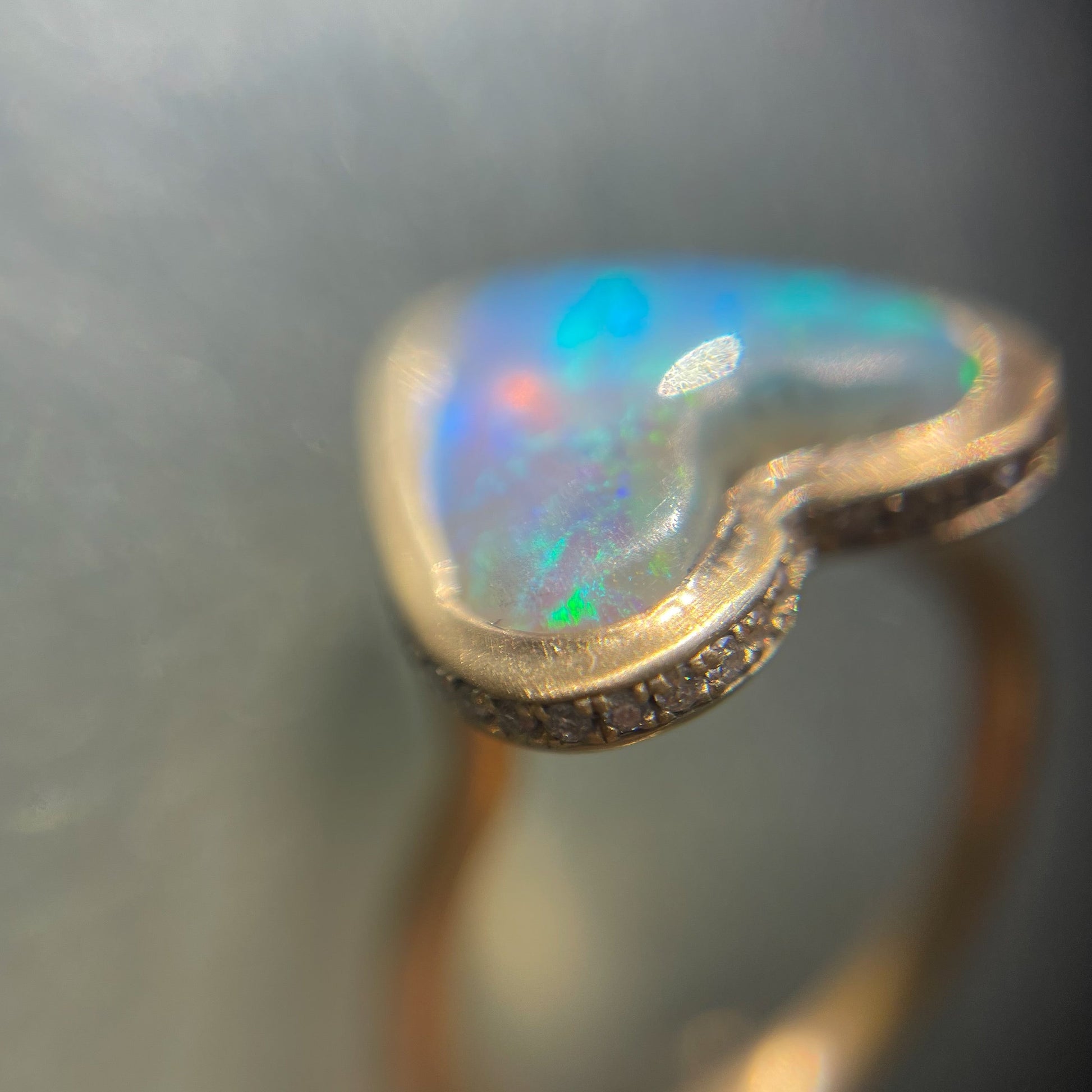 Close up shot of an Australian Opal Ring by NIXIN Jewelry. Shows the opal heart set in matte gold with pave diamonds.
