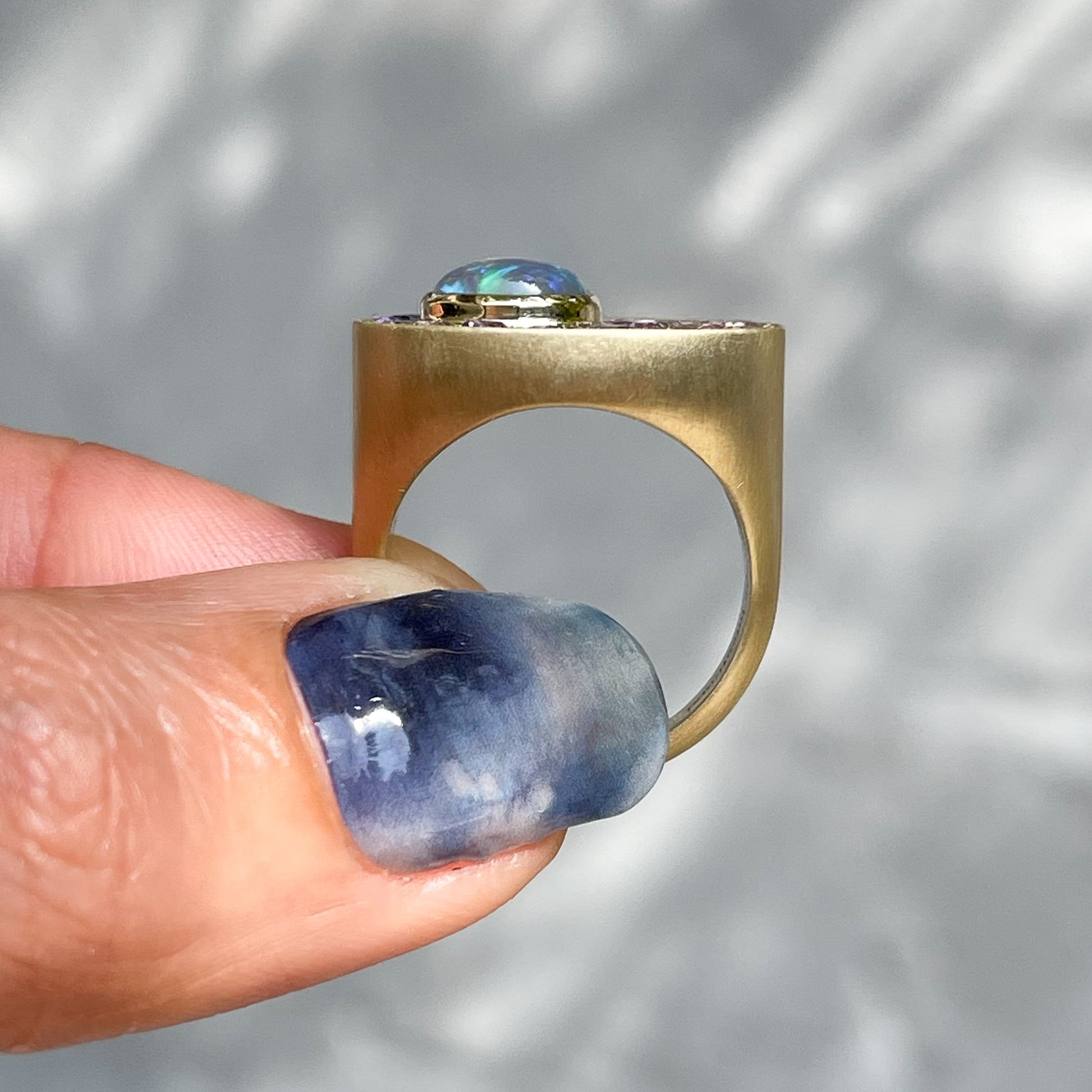 An Australian Opal Ring by NIXIN Jewelry held to show its side view. A modern opal ring designed as opal art.
