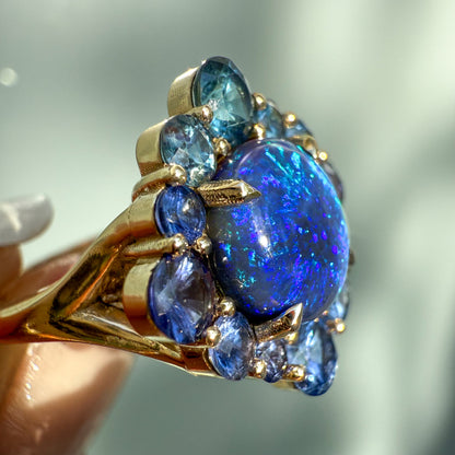 An Australian Opal Ring by NIXIN Jewelry. A close profile shot accentuates the brilliant fire of the lightning ridge opal and the dimensionality of the sapphire cluster. This highly collectible rare opal jewelry item offers true luxury and is one of the most sophisticated black opal rings available.