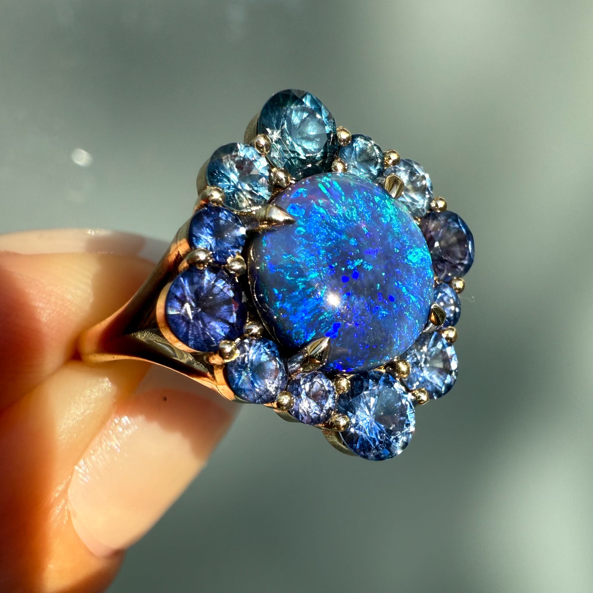 An Australian Opal Ring by NIXIN Jewelry. This unique opal jewelry piece features a round black opal from Lightning Ridge in a secure prong setting, capturing incredible light play. The gold opal ring is a highly desirable luxury ring that showcases the vibrant color spectrum of the natural opal.