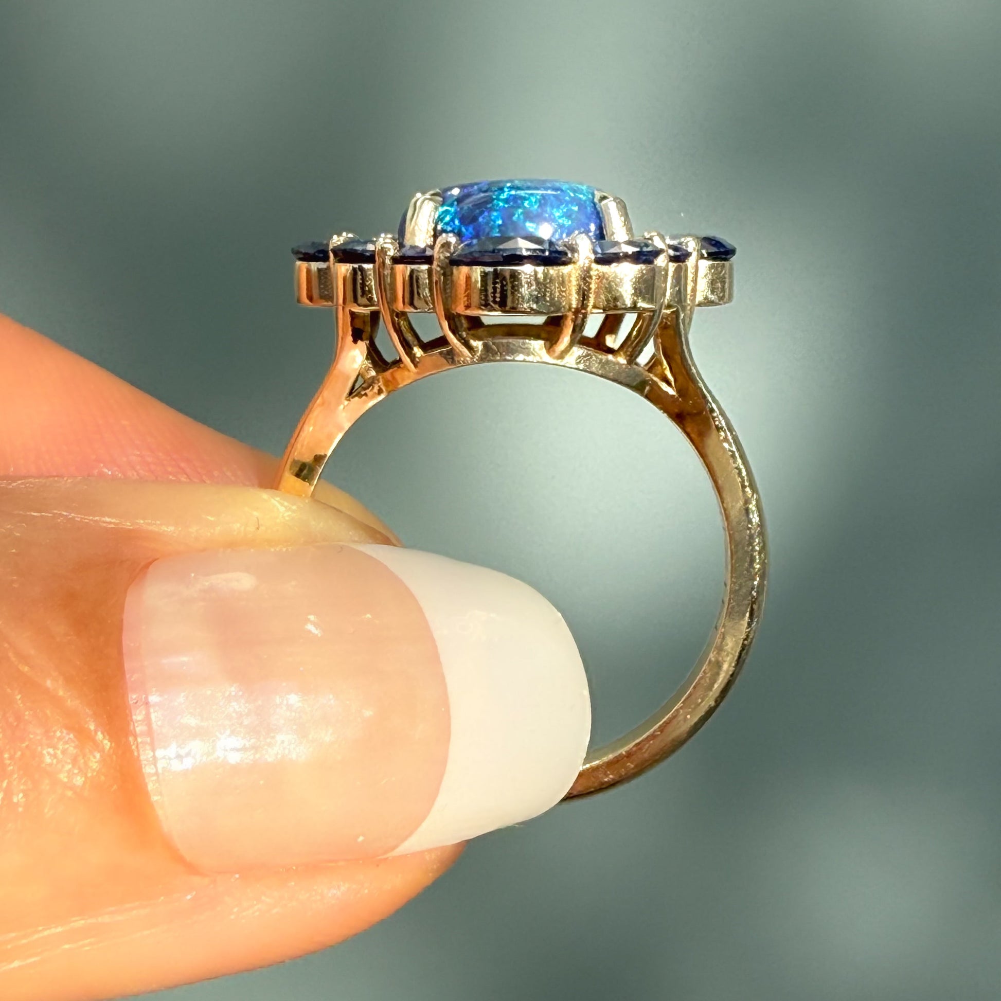An Australian Opal Ring by NIXIN Jewelry. This profile view on the hand emphasizes the elegant structure and height of the opal ring setting. It's a prime example of a women's luxury ring and unique jewelry, featuring a mesmerizing black opal of the highest quality.