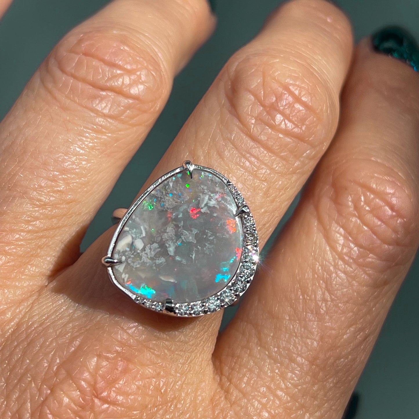 An Australian Opal Ring by NIXIN Jewelry in white gold with diamonds modeled on a hand.