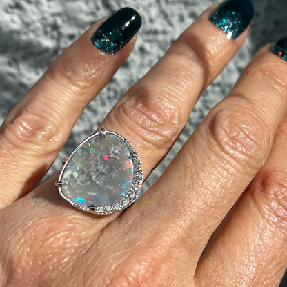 An Australian Opal Ring by NIXIN Jewelry. The opal and diamond ring is modeled on a hand.