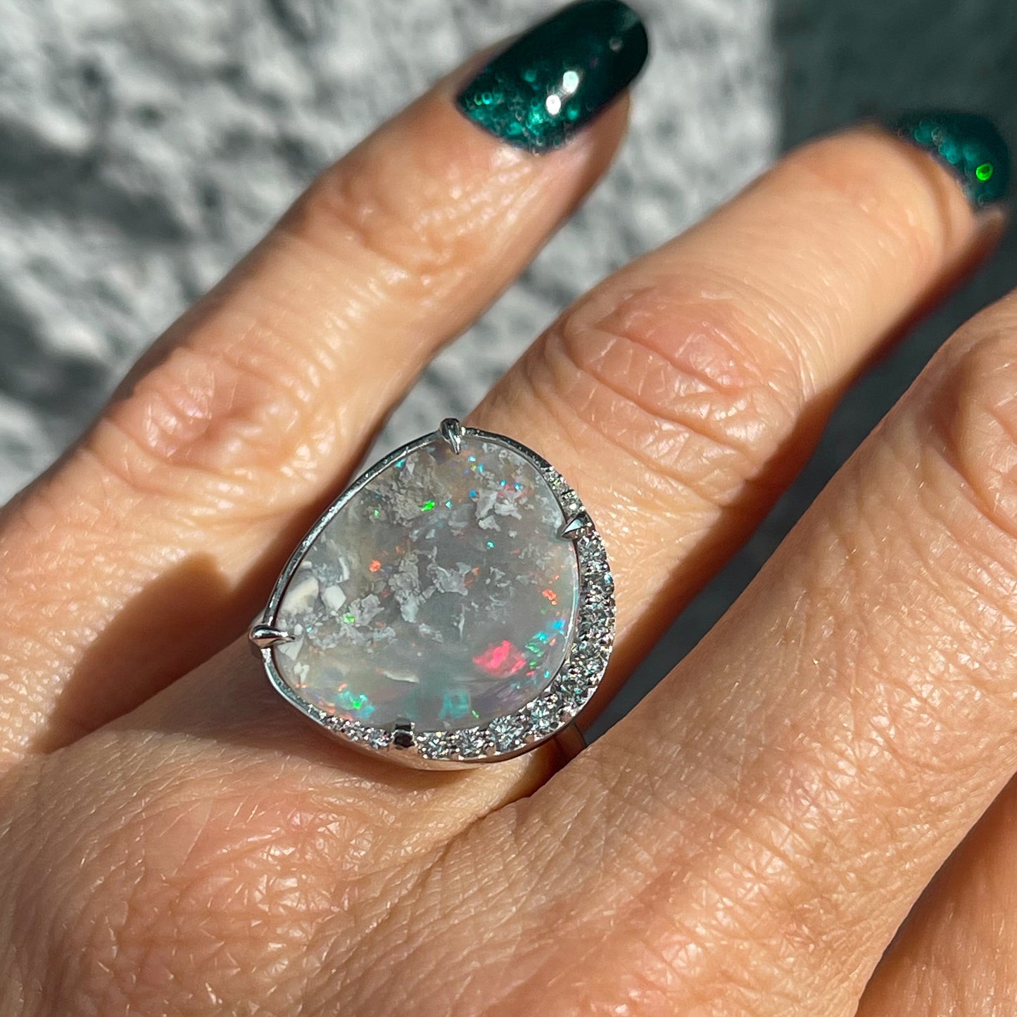 An Australian Opal Ring by NIXIN Jewelry. The white gold opal ring is shown on a hand.