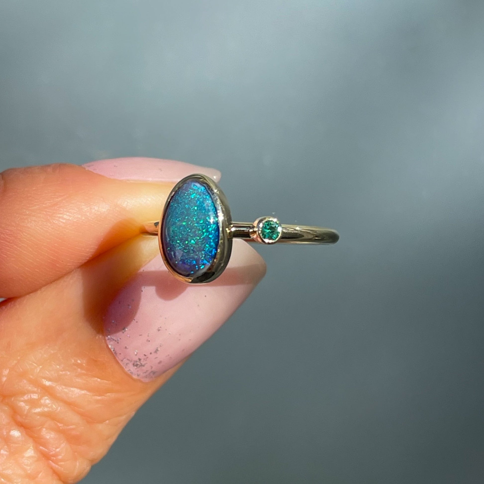 Side view of an Australian Opal Ring by NIXIN Jewelry. Shows the emerald and opal in bezel settings.