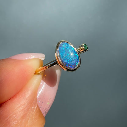 Angled shot of an Australian Opal Ring by NIXIN Jewelry. An opal and emerald ring in 14k gold.