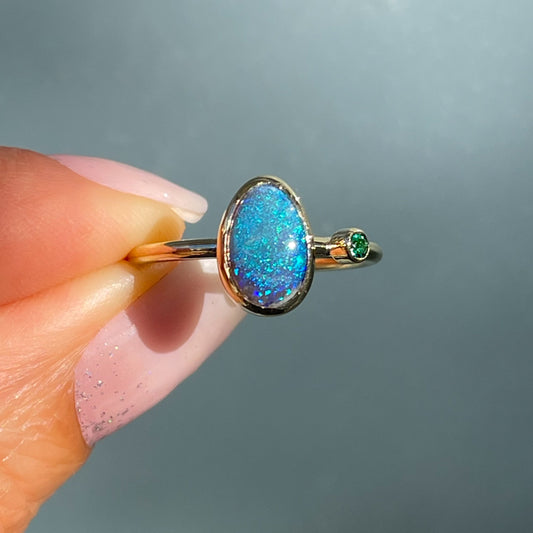 An Australian Opal Ring by NIXIN Jewelry. A black opal ring bezel set in gold with an emerald.