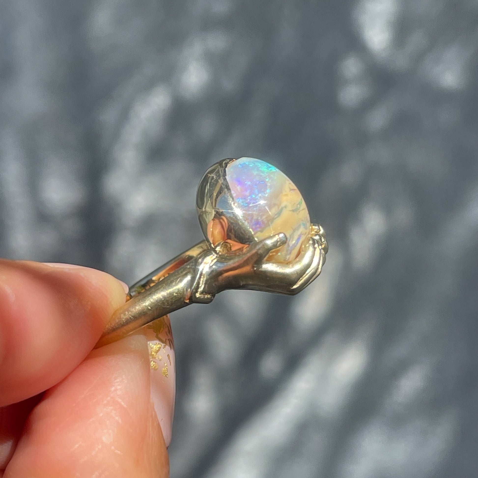 Profile view of an Australian Opal Ring by NIXIN Jewelry. The gold hand ring holds an opal stone.