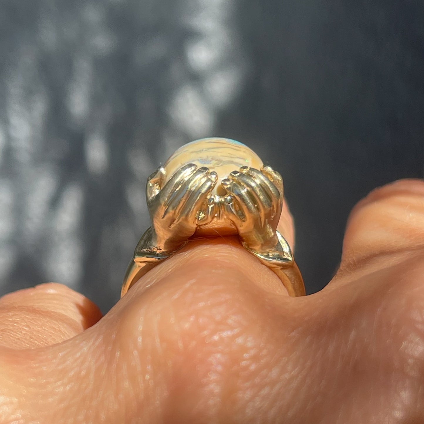 Side view of an Australian Opal Ring by NIXIN Jewelry modeled on the hand. The Boulder Opal is set in gold hands.