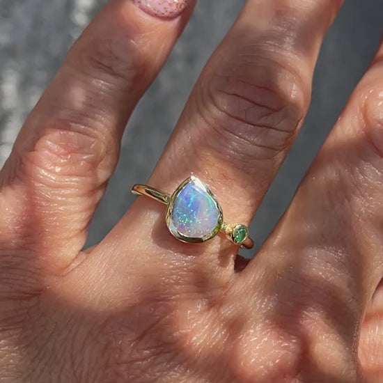 Video of an Australian Opal Ring modeled on a hand. A gold opal ring made with a Black Opal and and emerald.