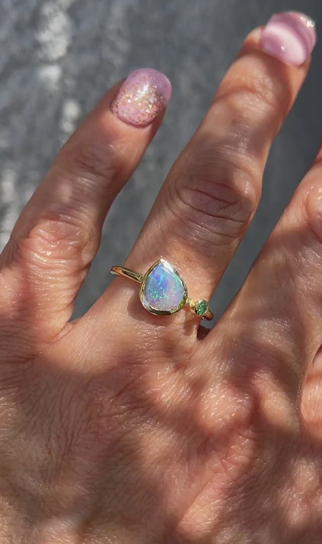 Video of an Australian Opal Ring modeled on a hand. A gold opal ring made with a Black Opal and and emerald.