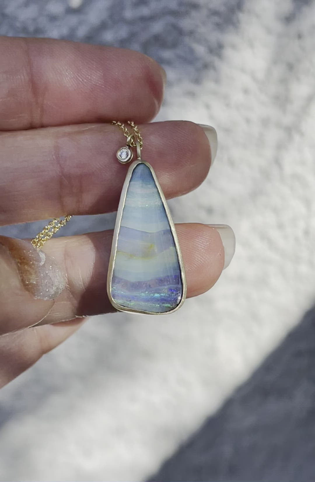 Video of seascape matte gold blue opal necklace held in sunlight