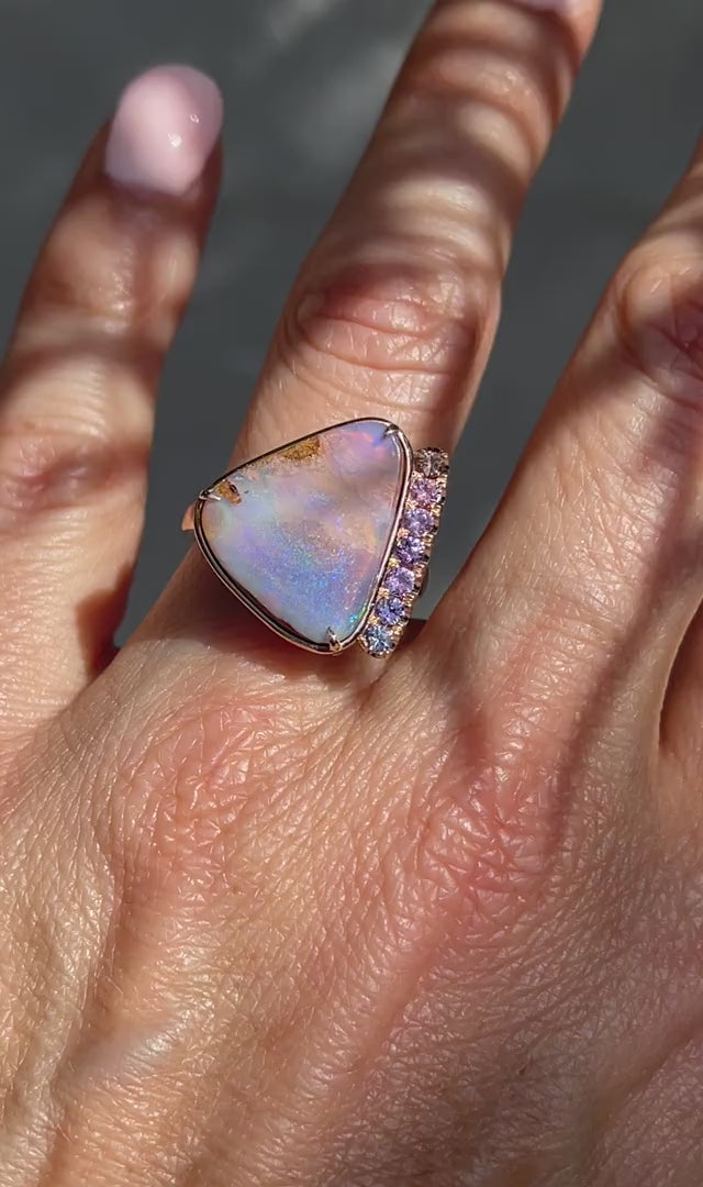 A video of an Australian Opal Ring by NIXIN Jewelry modeled on the hand. The sapphire and opal ring is made in rose gold with a Boulder Opal and ombré sapphires. 