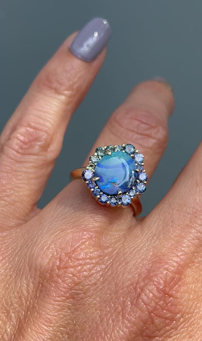 Video of Australian Opal Ring by NIXIN Jewelry modeled on hand. Blue, green and teal sapphires sparkle around a blue opal ring.