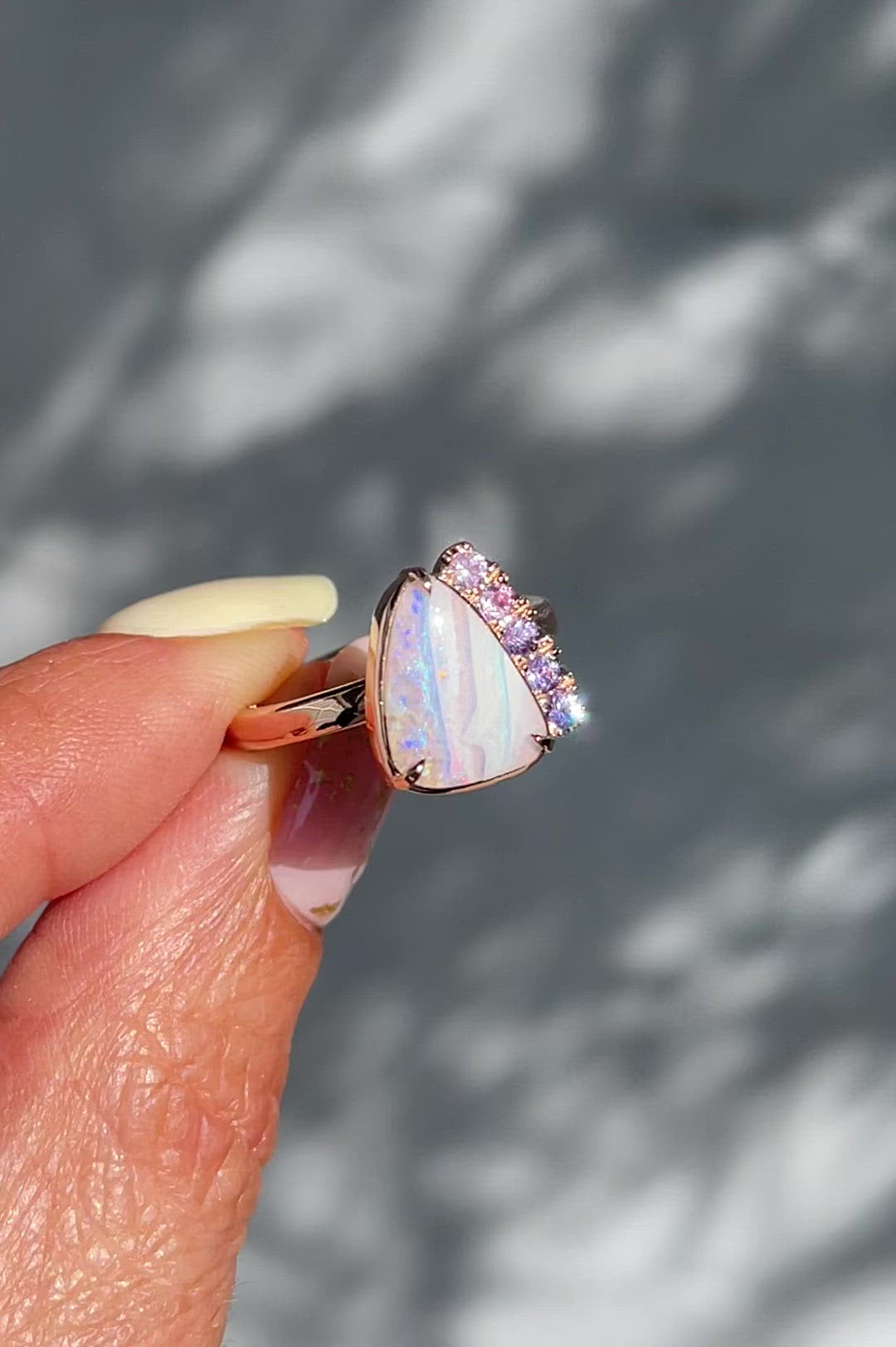 Video of Australian Opal Engagement Ring by NIXIN Jewelry held in sun. Real opal ring with pink and purple sapphires.