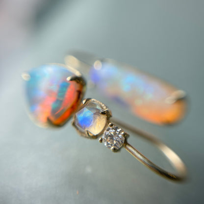 Close up of mismatched opal drop earrings by NIXIN Jewelry