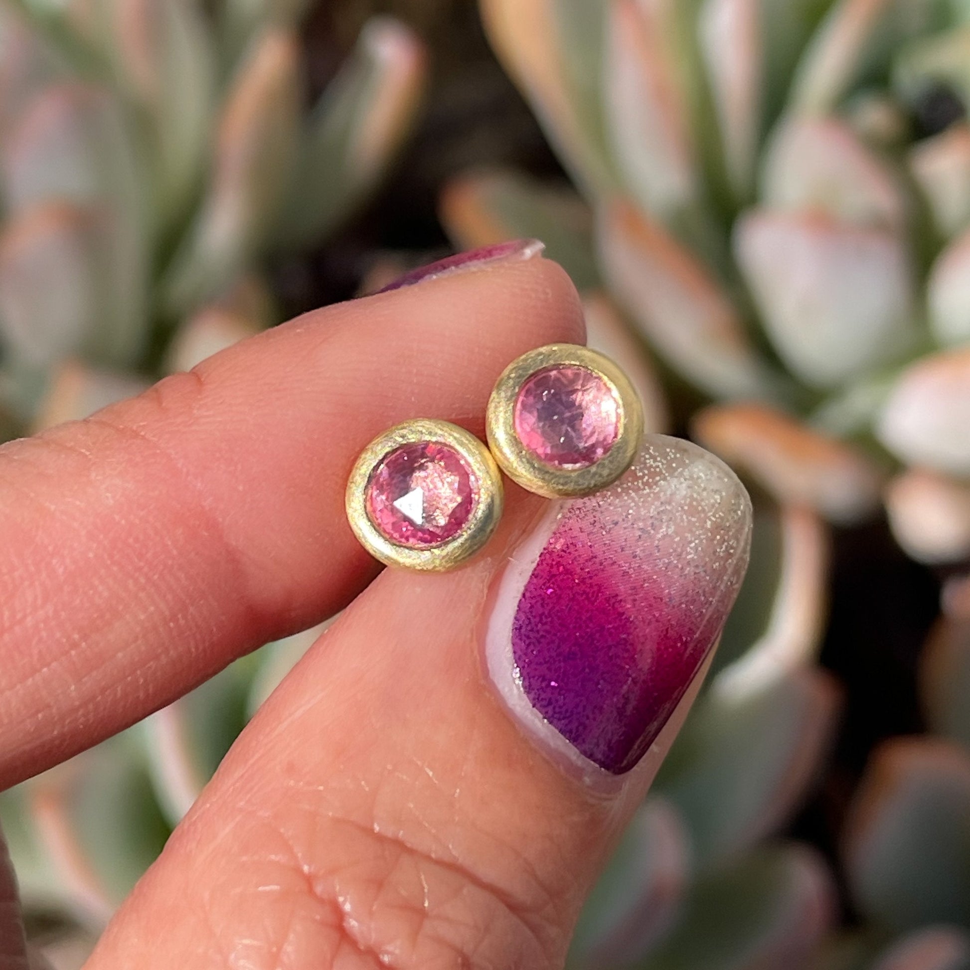 Pink stud earrings by NIIXN Jewelry in front of succulents