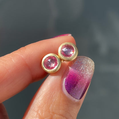 Pink sapphire earrings by NIXIN Jewelry held in sunlight