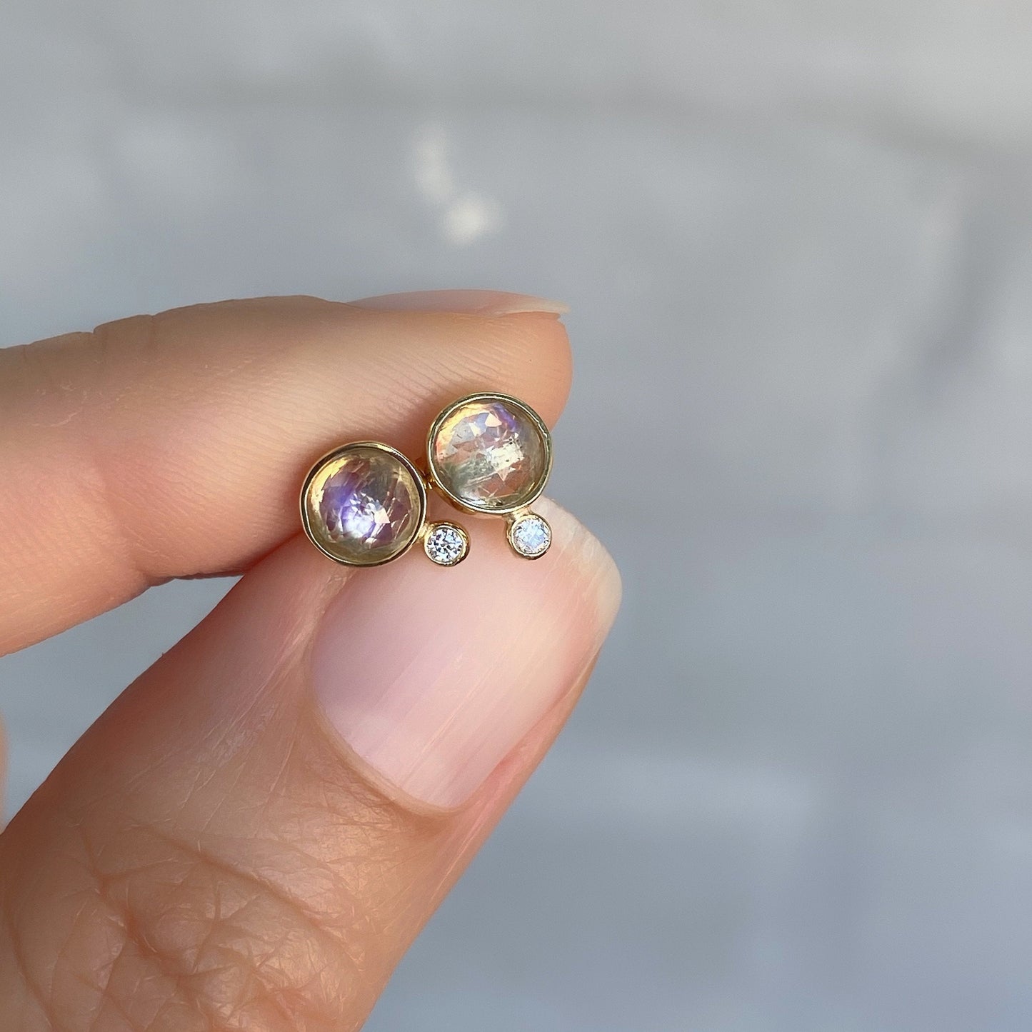 moonbeam moonstone diamond stud earrings in yellow gold in hand for scale