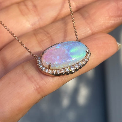 An Australian Opal Necklace by NIXIN Jewelry shown at an angle resting on a hand. A green and purple opal necklace.