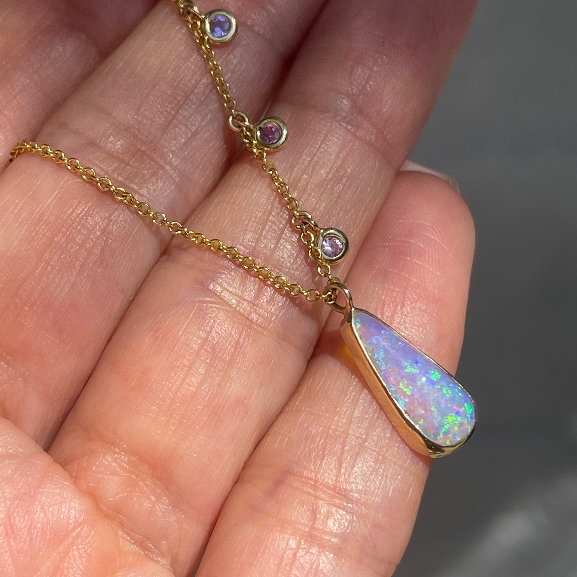 Australian Opal Necklace by NIXIN Jewelry resting on palm. Side of opal pendant showing bezel edge.