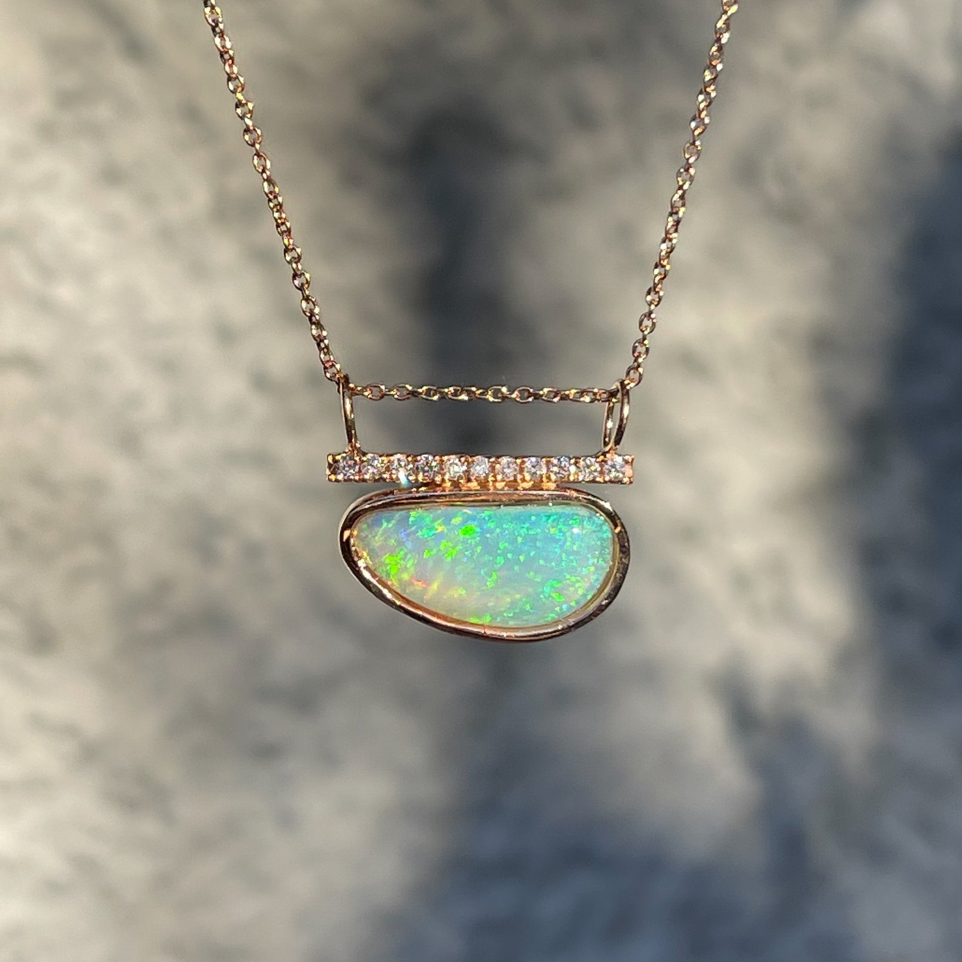 Green opal necklace by NIXIN Jewelry in front of grey wall