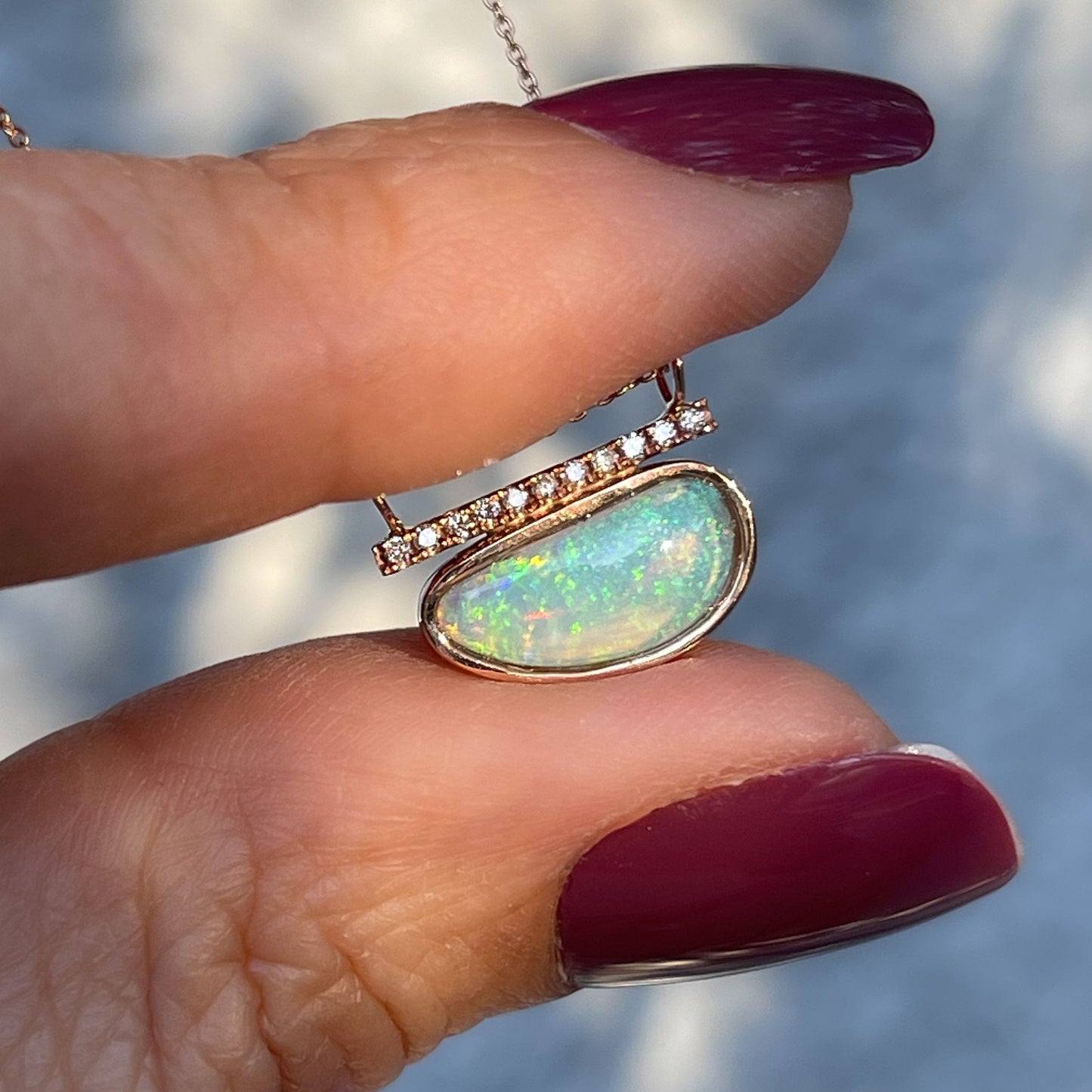 Crystal opal necklace by NIXIN Jewelry held up in sun