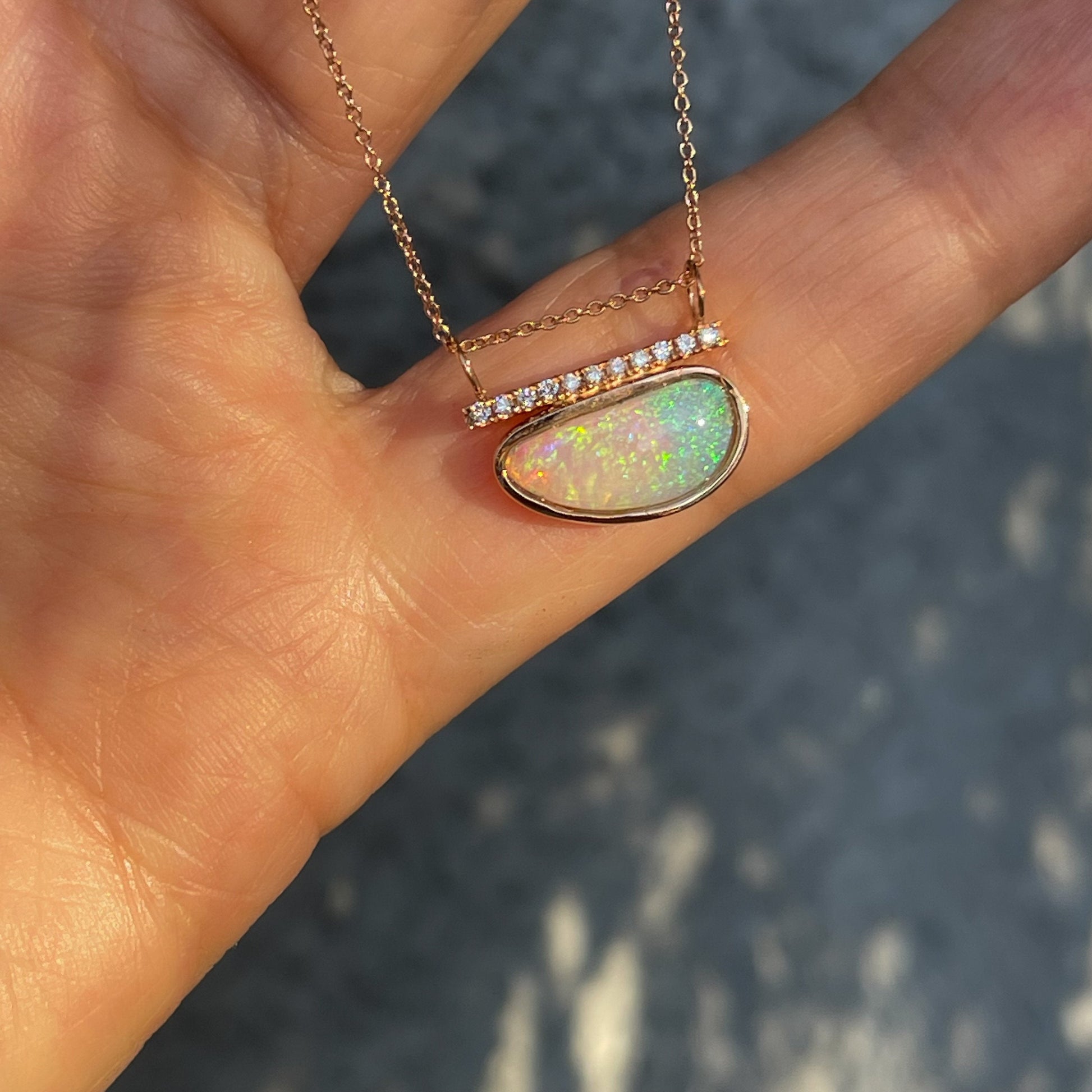 Rose gold opal necklace by NIXIN Jewelry against hand