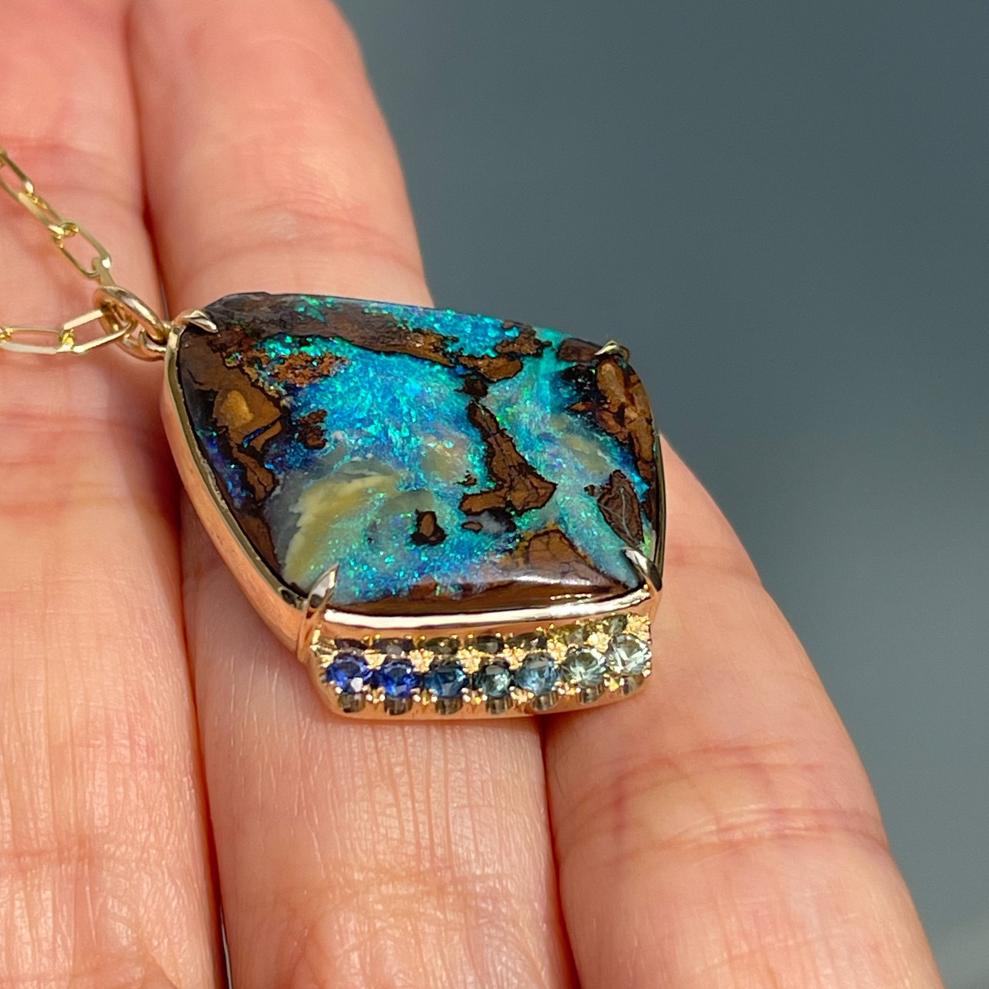 Boulder opal pendant by NIXIN Jewelry against hand