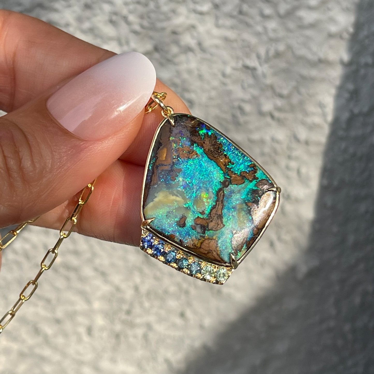 Large opal pendant with green opal by NIXIN Jewelry held in sunlight