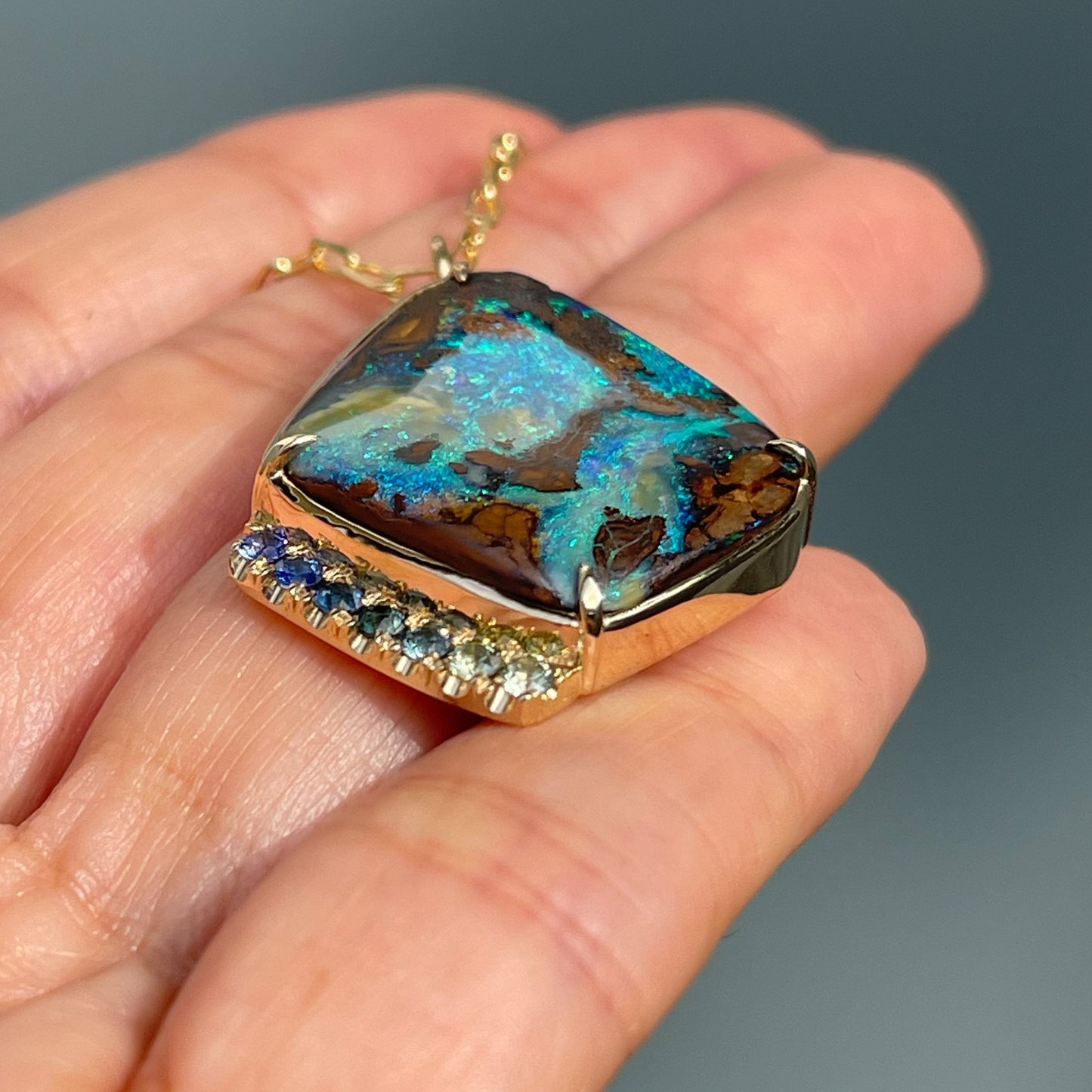 Gold opal necklace by NIXIN Jewelry on hand from angle