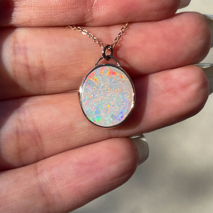 An Australian Opal Necklace by NIXIN Jewelry. The opal pendant necklace is resting on a hand.