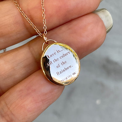 The back of an Australian Opal Necklace by NIXIN Jewelry with a special message engraved in solid gold. The rose gold pendant necklace is resting on a hand.