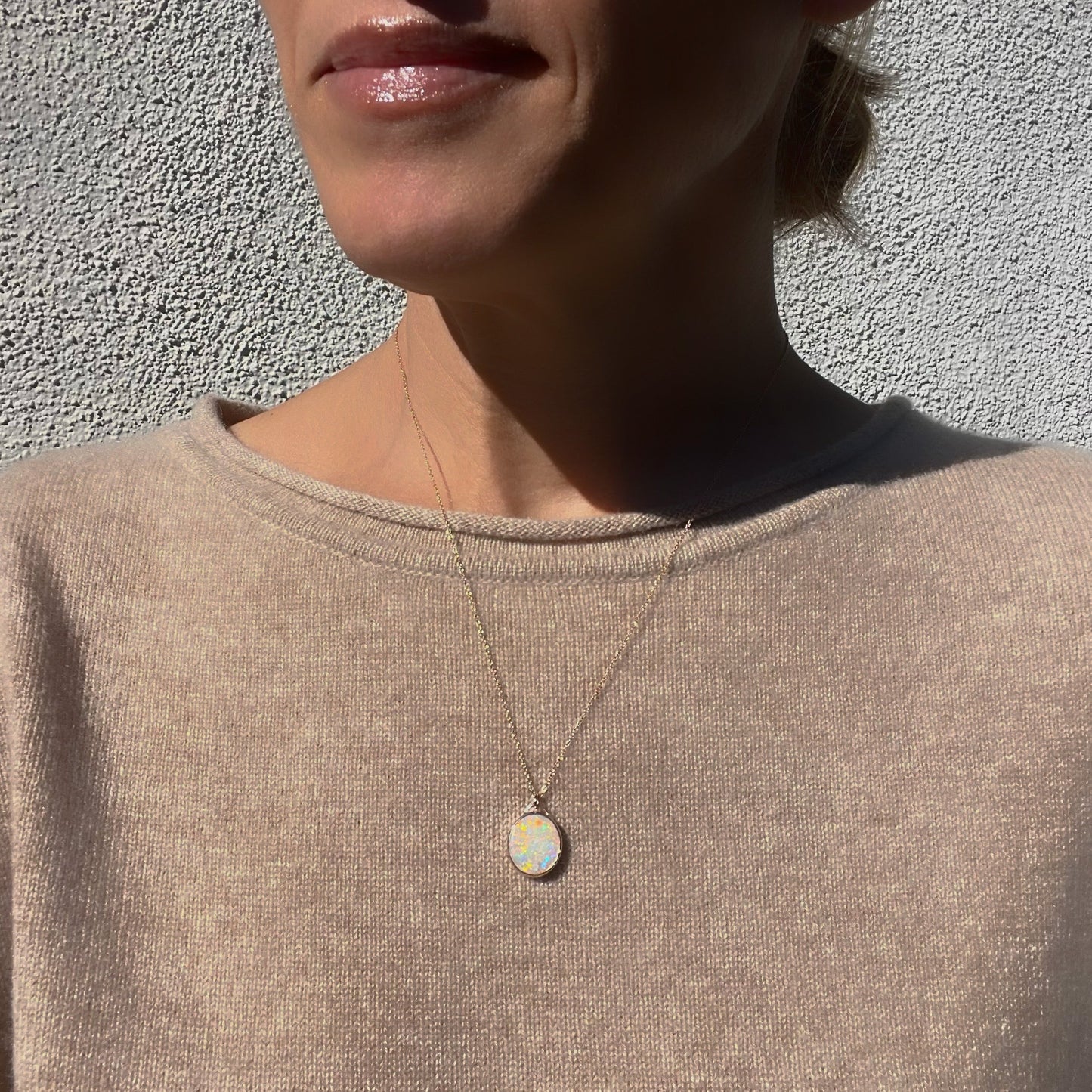 An Australian Opal Necklace by NIXIN Jewelry worn by a model. An oval opal pendant set in 14k rose gold.