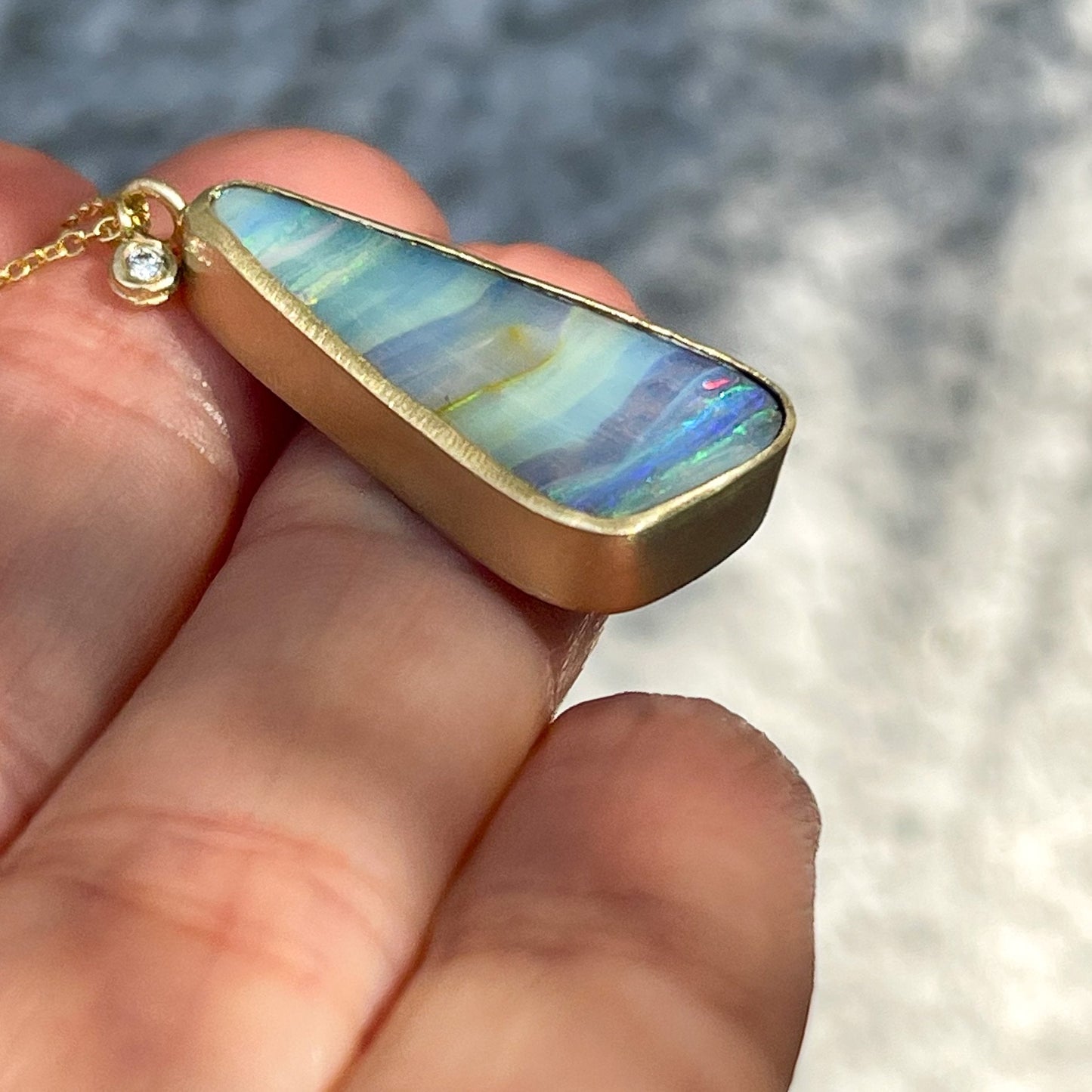 Gold opal necklace by NIXIN Jewelry shown in profile