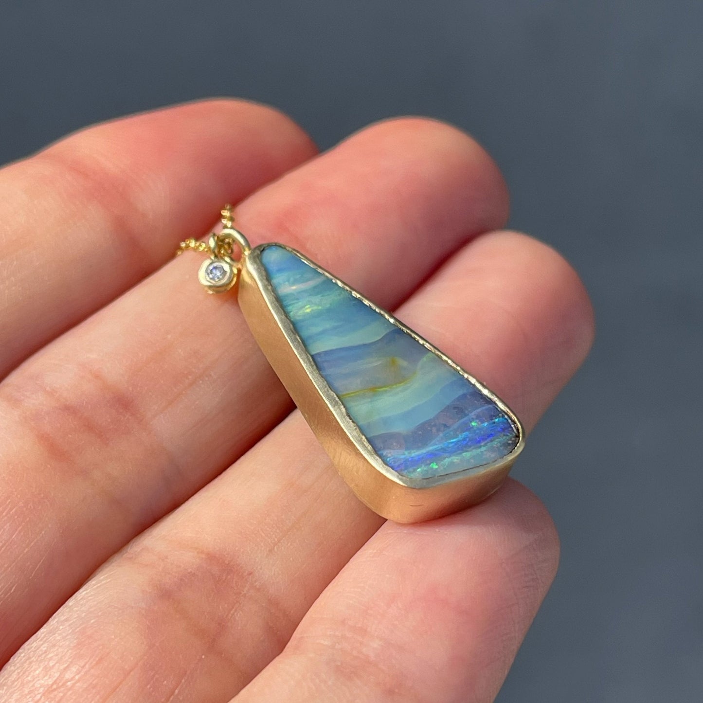 Matte gold and blue opal necklace by NIXIN Jewelry shown at angle