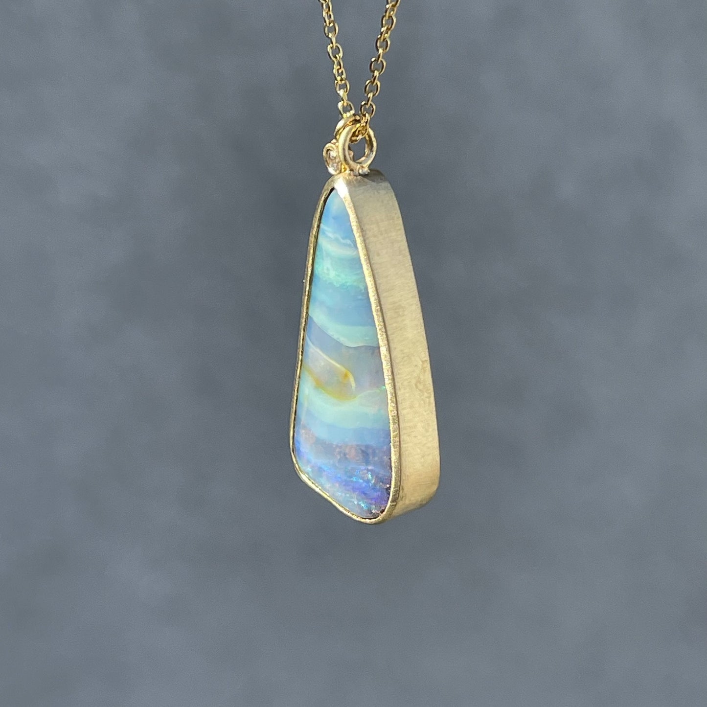 Opal pendant with boulder opal by NIXIN Jewelry hanging in sunlight