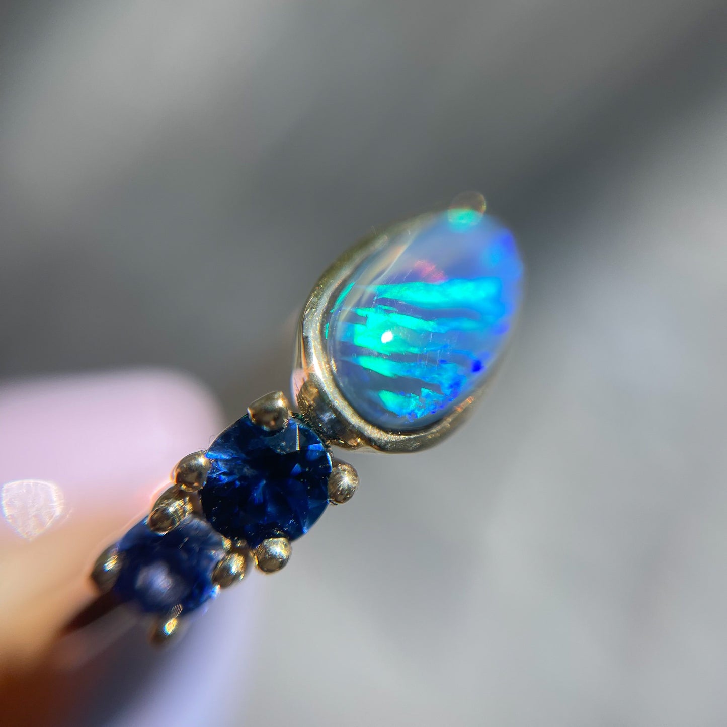Black Opal Ring by NIXIN Jewelry shown magnified. Blue opal ring in 14k gold.