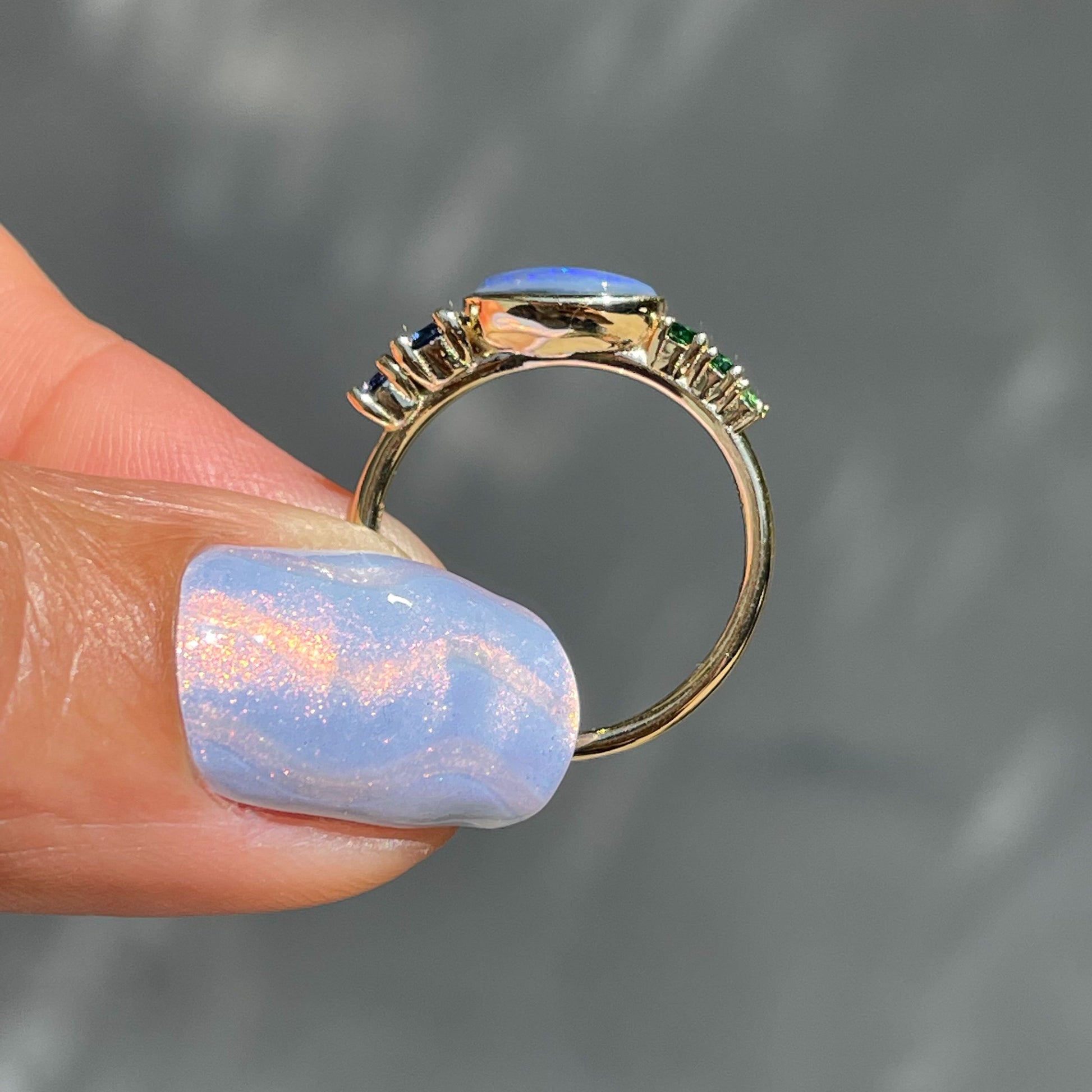 Black Opal Ring by NIXIN Jewelry held in profile. Gold opal ring.