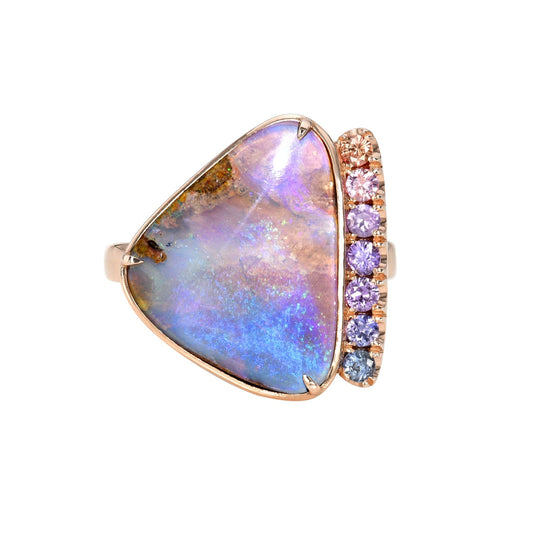 An Australian Opal Ring by NIXIN Jewelry against a white backdrop. It's a sapphire and opal ring made in rose gold.