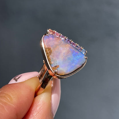Side view of an Australian Opal Ring by NIXIN Jewelry. Shows off the rose gold frame and prong setting of the purple opal and the sapphire border.
