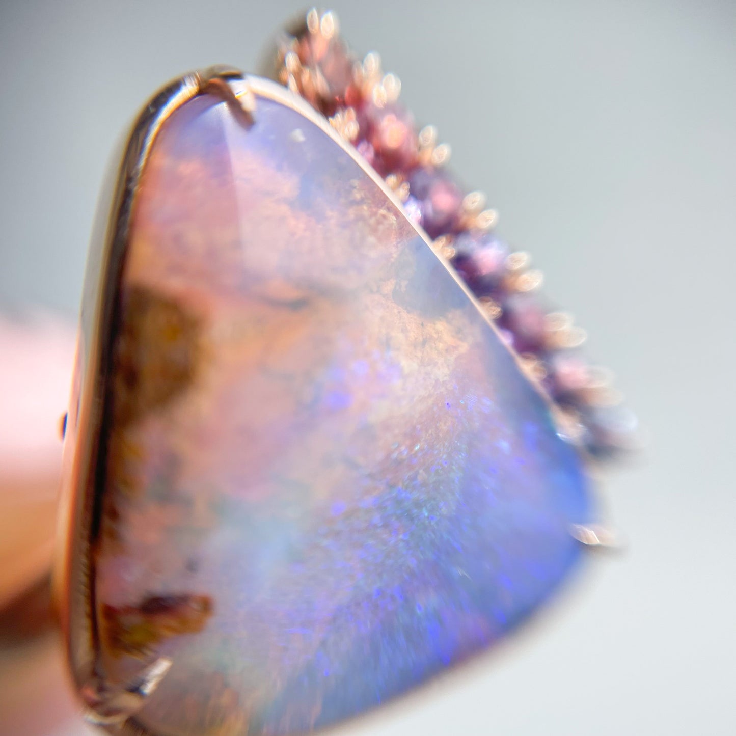 Close up shot of an Australian Opal Ring by NIXIN Jewelry. Image shows the pink and blue of the Boulder opal and the sapphire gradient.